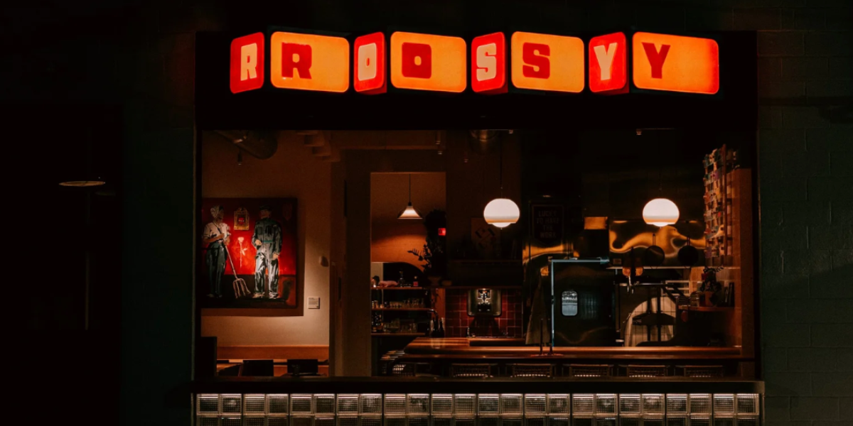 ROSY storefront at night, illuminated marquee sign above the entrance